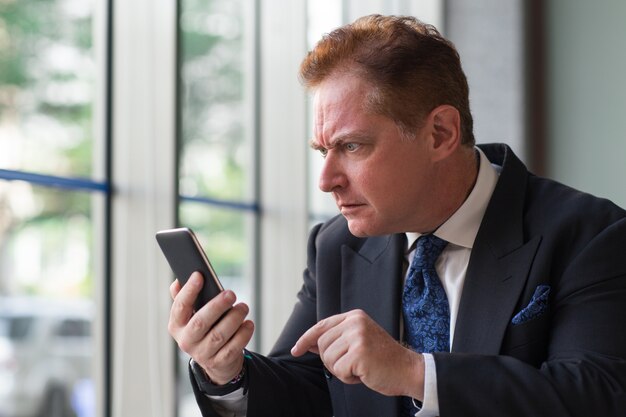 Surprised senior businessman reading message