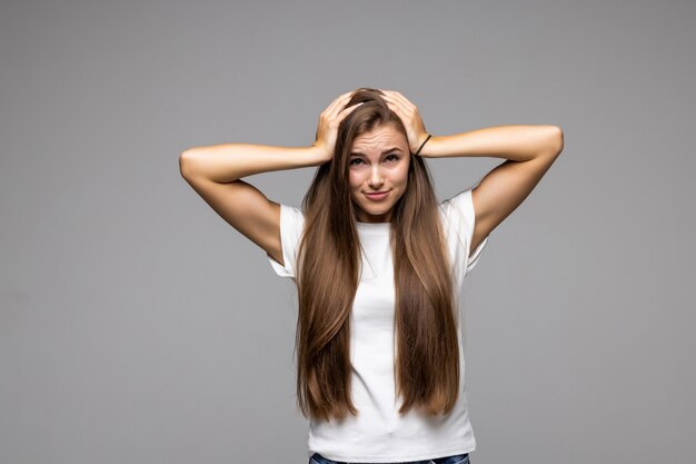 Surprised shocked young woman standing with opened mouth isolated on grey background