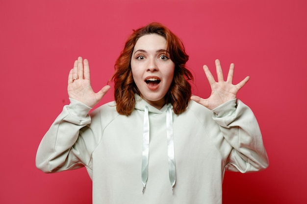 Surprised showing different numbers young beautiful girl in white sweater isolated on pink background