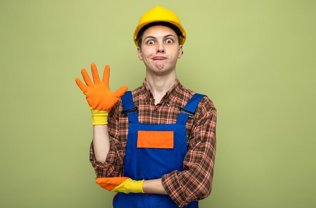 Surprised showing five young male builder wearing uniform with gloves 