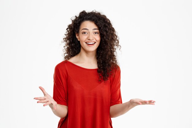  surprised smiling curly girl over white wall