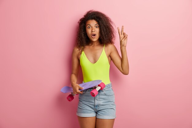 Surprised sportive female posing with skateboard