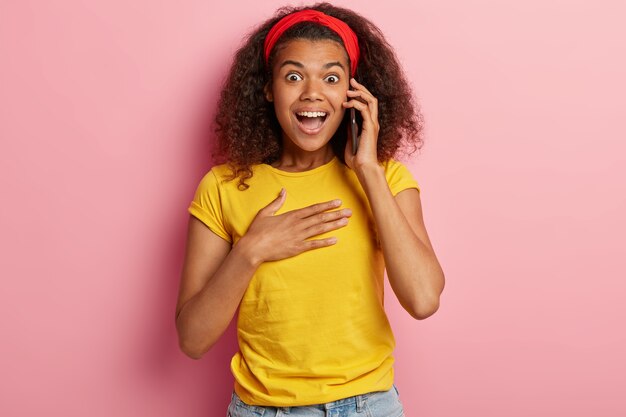 Surprised teenage girl with curly hair posing in yellow tshirt