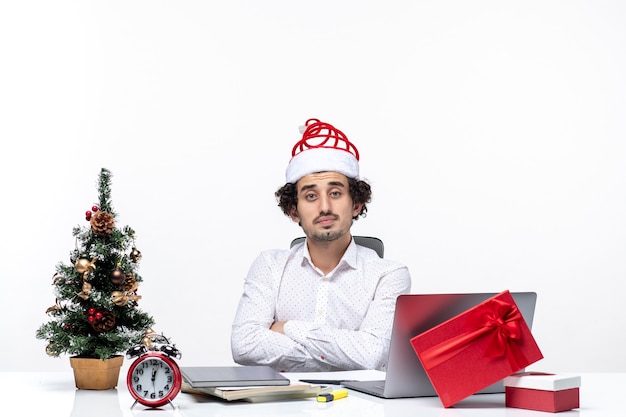 흰색 바탕에 사무실에서 카메라에 포즈를 취하는 재미있는 산타 클로스 모자와 놀된 피곤 된 젊은 사업가
