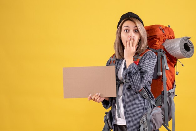 удивленная путешественница женщина с рюкзаком держит картон
