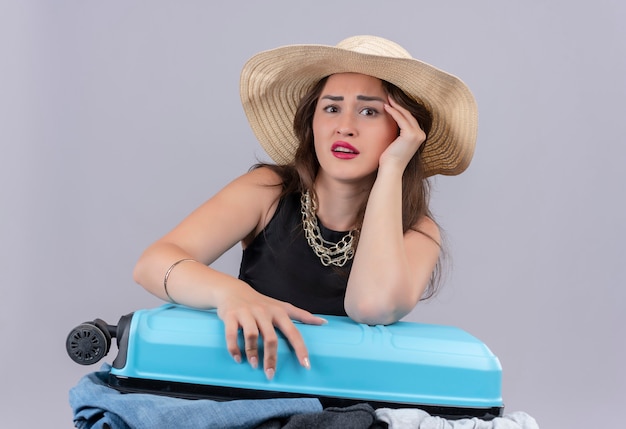 Surprised traveler young girl wearing black undershirt in hat holding open suitcase on white background