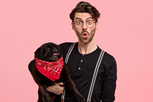 Surprised unshaven man in black shirt with braces