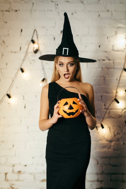 Free photo surprised witch with pumpkin basket