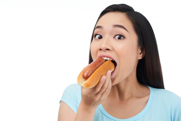 Удивленная женщина ест хот-дог
