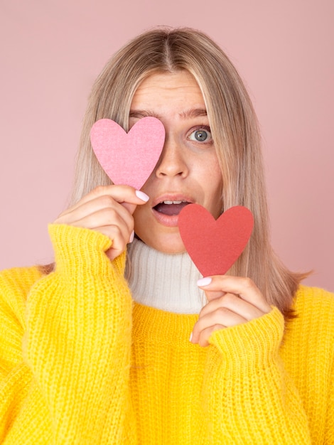 Donna sorpresa che posa con i cuori di carta