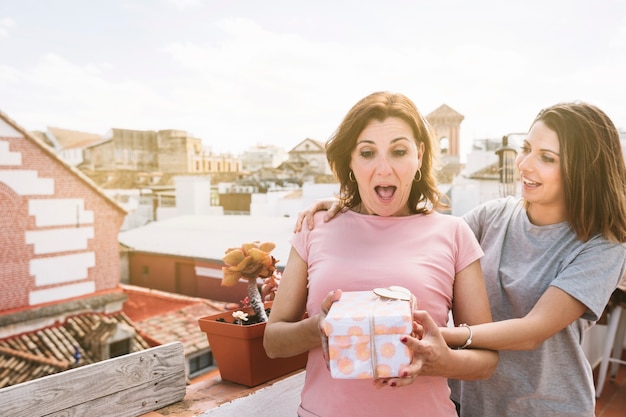 Surprised woman receiving gift from woman