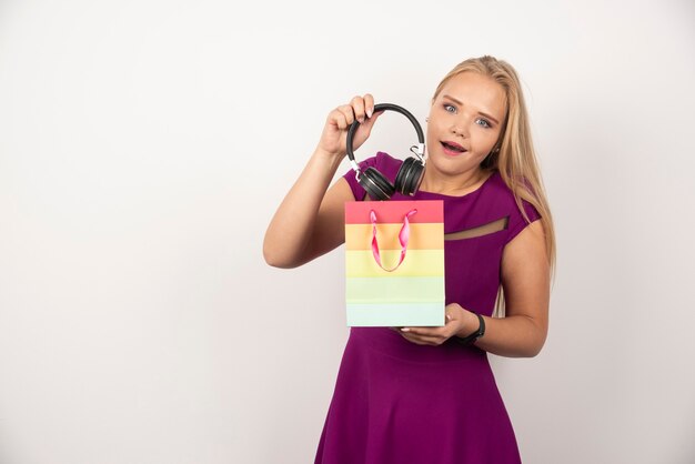 Surprised woman taking headphones out of gift bag.