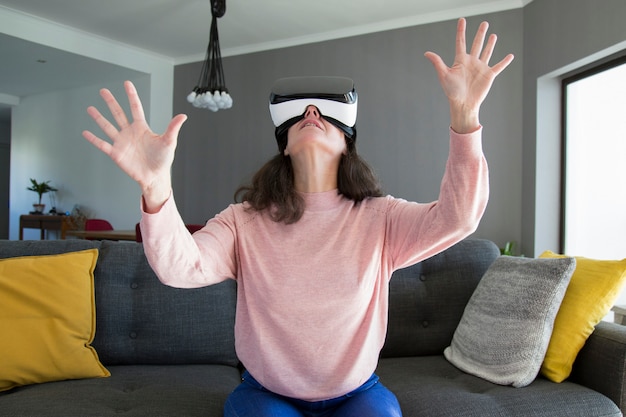 Free photo surprised woman in virtual reality goggles gesturing hands