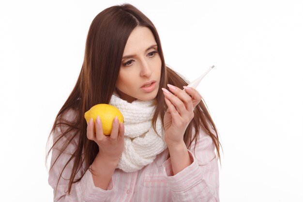 Удивленная женщина с лимоном в руке и глядя на термометр