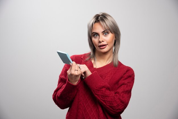 Surprised woman with memo pad looking at camera.