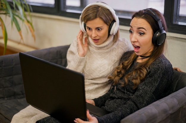 Surprised women wearing headphones looking at laptop