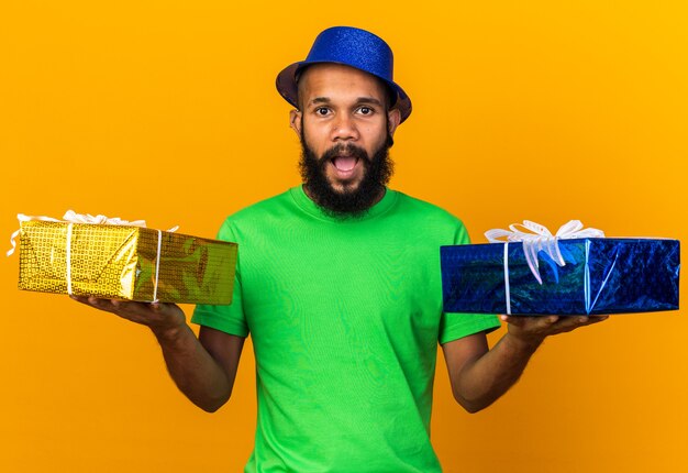 Удивленный молодой афро-американский парень в шляпе с подарками