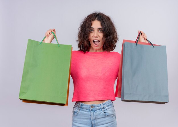 Surprised young beautiful woman holding carton bags on isolated white wall