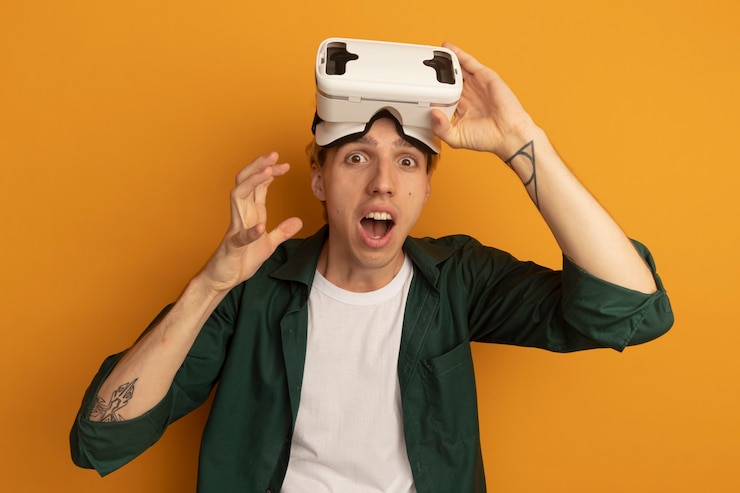 Free Photo surprised young blonde guy wearing green t-shirt and vr headset