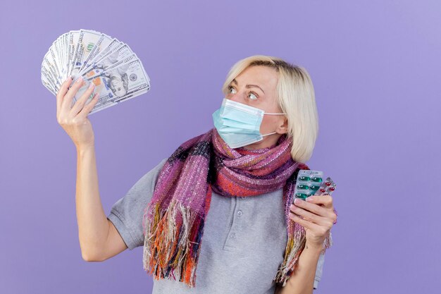 Surprised young blonde ill slavic woman wearing medical mask and scarf