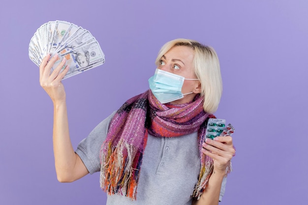 Surprised young blonde ill slavic woman wearing medical mask and scarf