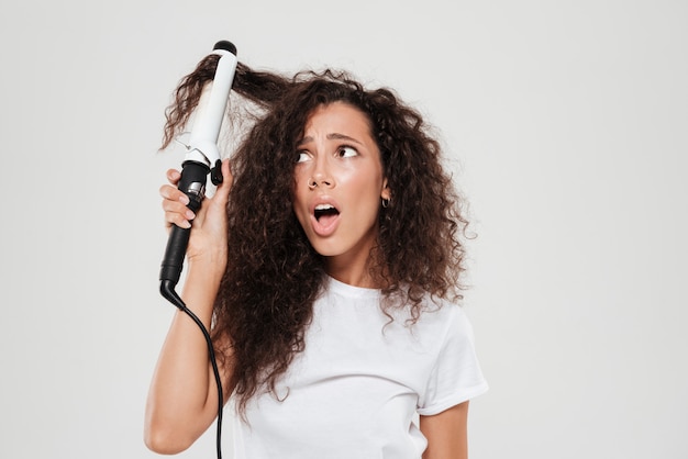 Surprised young brunette woman straighten her hair and looking away