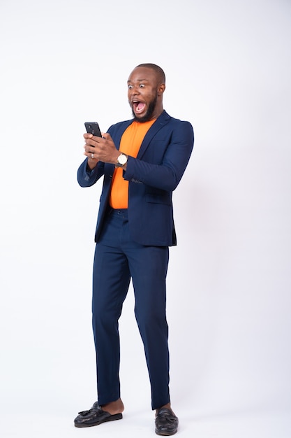 Surprised young businessman celebrating while looking at his phone