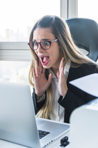 オフィスでラップトップを見て驚いた若い実業家