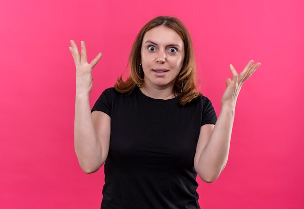 Surprised young casual woman with raised hands on isolated pink wall