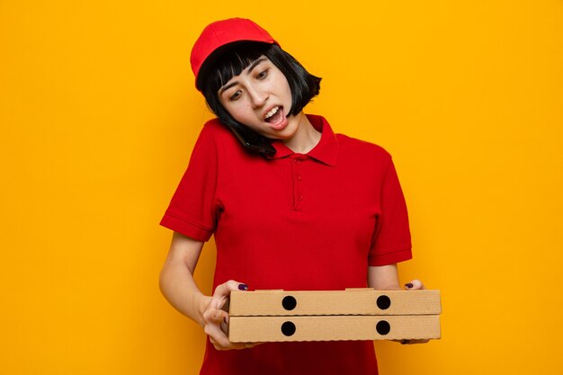 Surprised young caucasian delivery girl talking on phone holding pizza boxes 