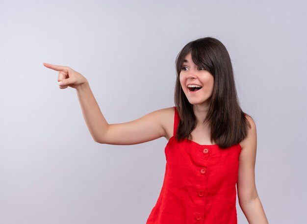 Surprised young caucasian girl pointing finger to the side and looking to the side on isolated white background