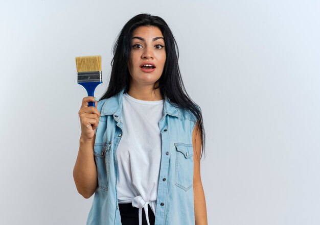 Surprised young caucasian woman holds painting brush