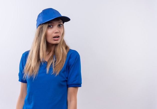 удивленная молодая доставщица в синей форме и кепке