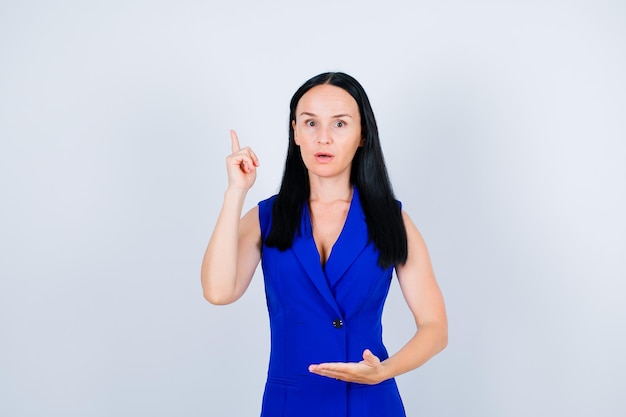 Surprised young girl is pointing up with forefinger on white background