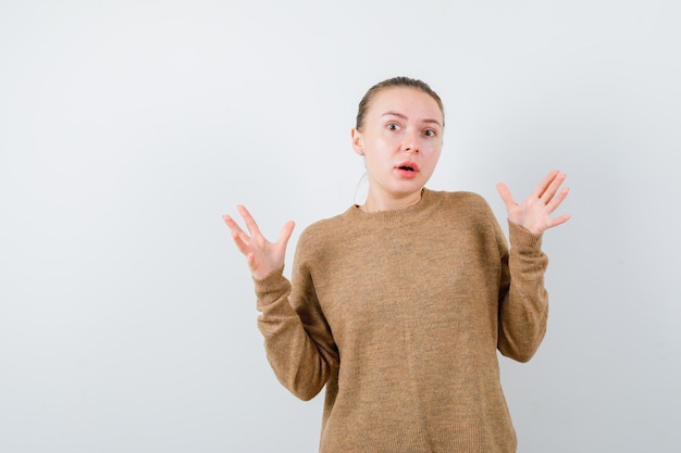 The surprised young girl opens her hands on white background