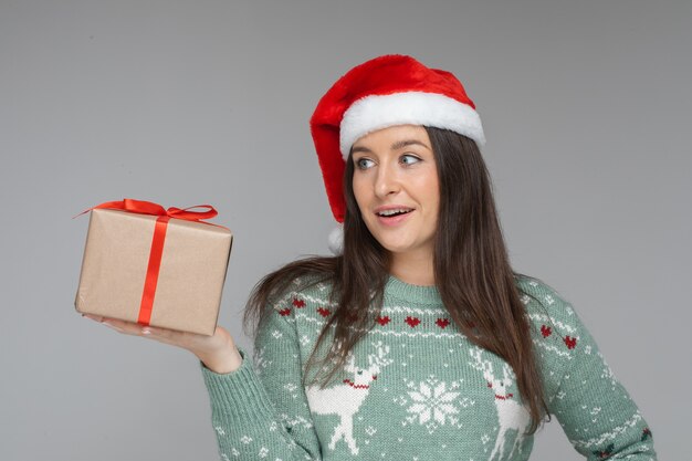 Surprised young girl in santa hat with gift