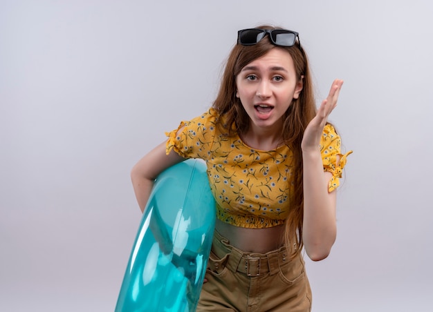 Surprised young girl wearing sunglasses on head holding swim ring on isolated white wall with copy space