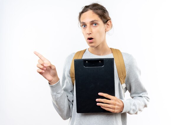 Удивленный молодой парень студент носить рюкзак, держа точки буфера обмена сбоку