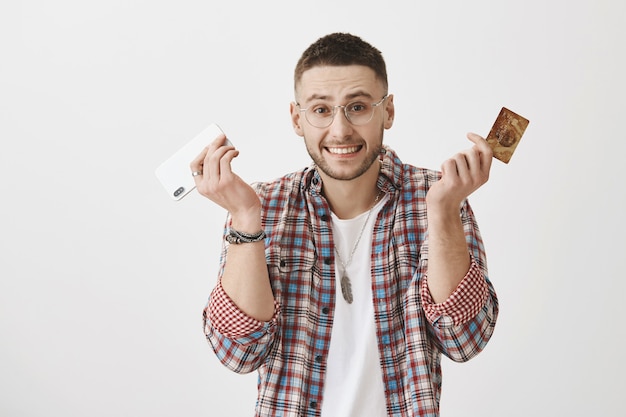 Удивленный молодой парень в очках позирует со своим телефоном и картой