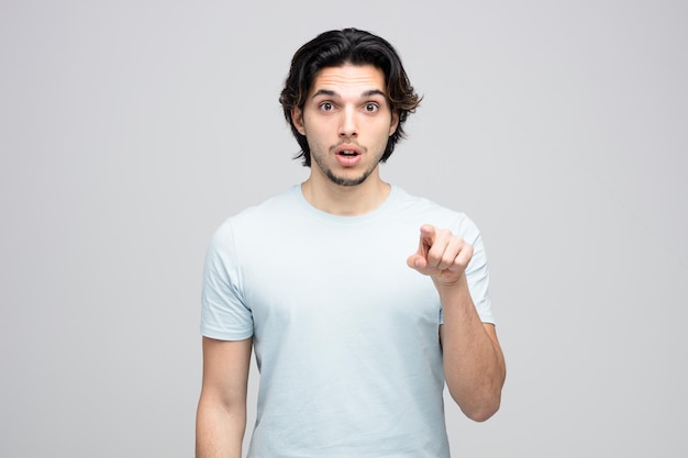 surprised young handsome man looking and pointing at camera isolated on white background