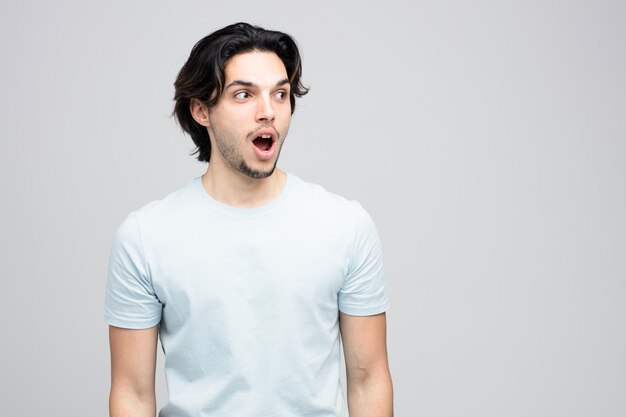 Surprised young handsome man looking at side isolated on white background with copy space