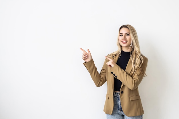 Surprised young happy woman pointing standing white background fascinated