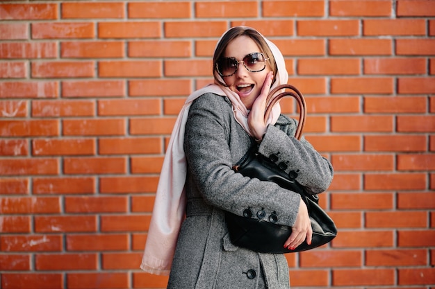 Surprised young lady with brick wall background