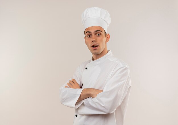 Surprised young male cook wearing chef uniform crossing hands with copy space