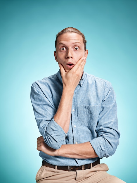 The surprised young man over blue background