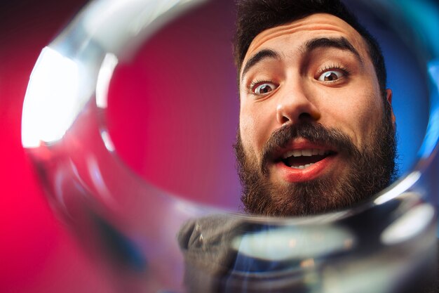 The surprised young man in party clothes posing with glass of wine.