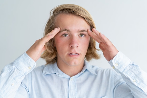 Surprised young man touching temples