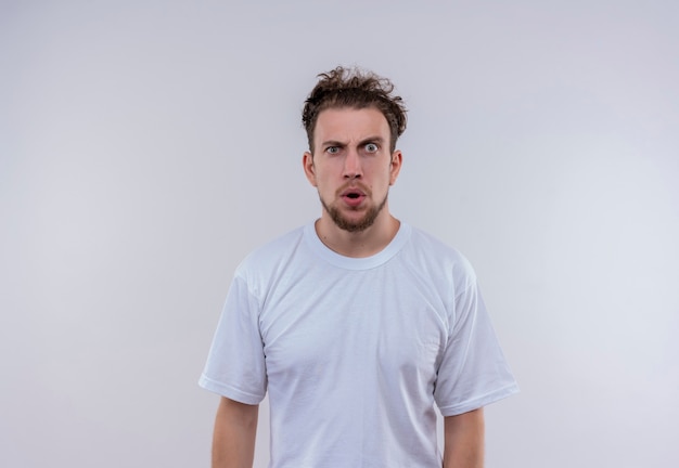 удивленный молодой человек в белой футболке на изолированной белой стене