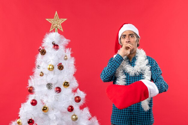 Surprised young man with santa claus hat in a blue stripped shirt and showing his christmas sock