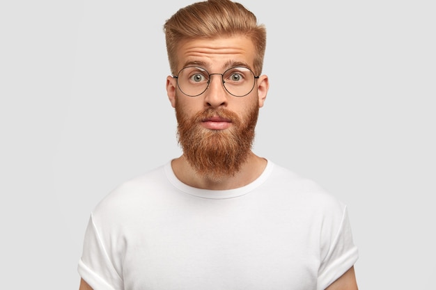 surprised young man with trendy haircut, has ginger beard and mustache